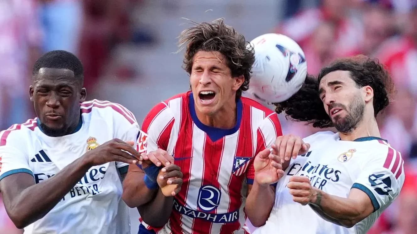 Players from Atletico and Real Madrid contesting for the ball Players from Atletico and Real Madrid contesting for the ball