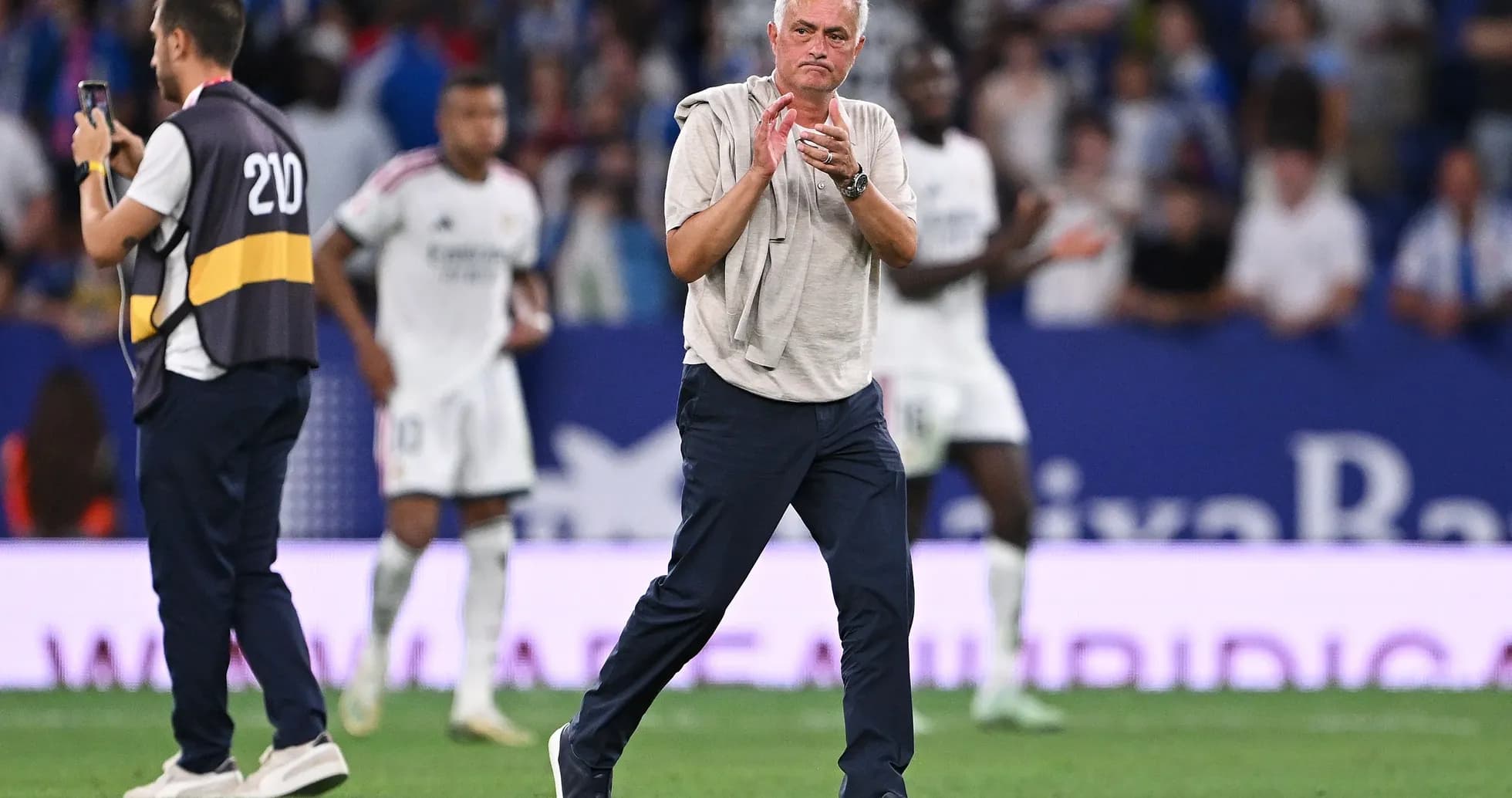 Coach applauding during a match with players in background Coach applauding during a match with players in background